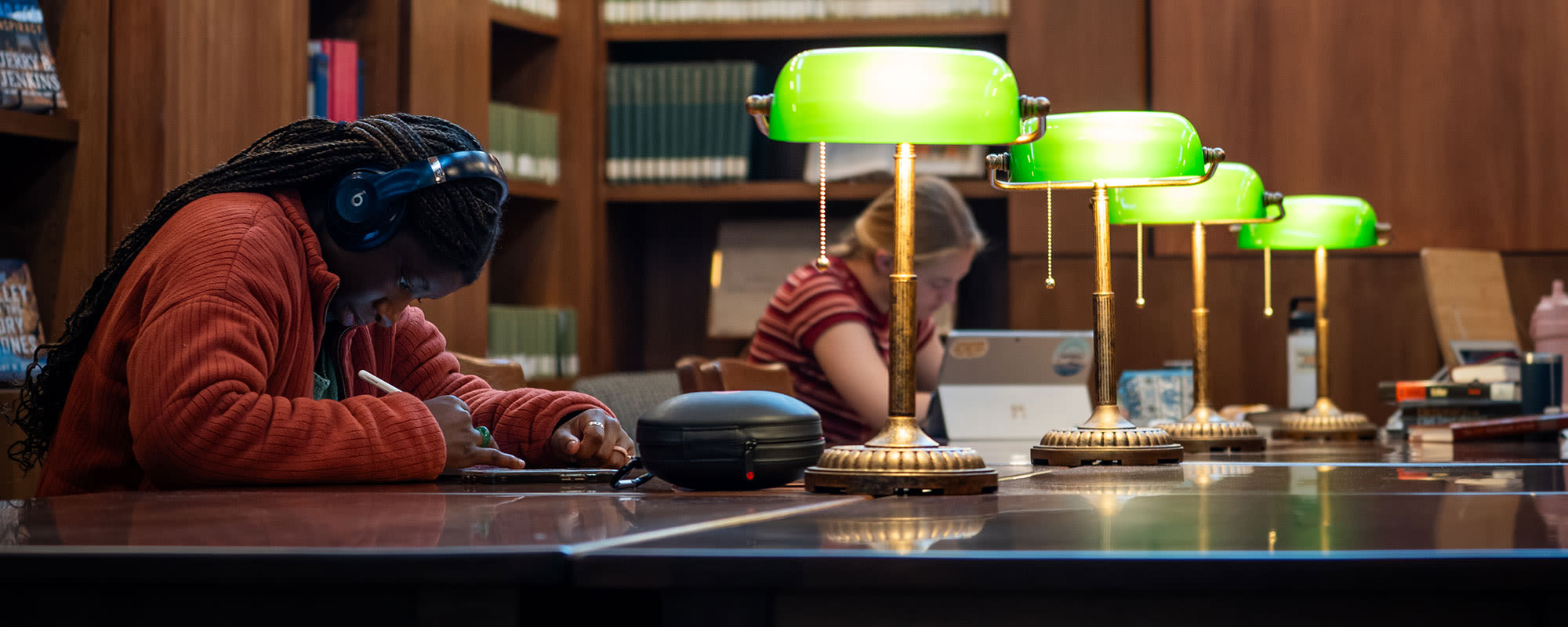 Section background image: students working at a long table with lamps in the center