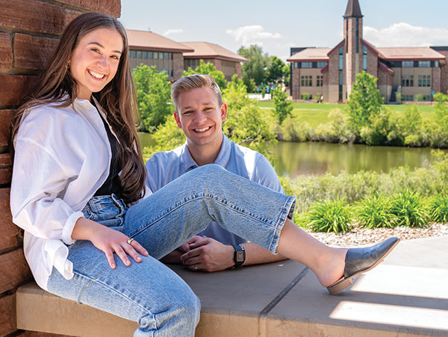 endowment fund recipients on campus smiling and sitting on a stone wall with the armstrong center in the background