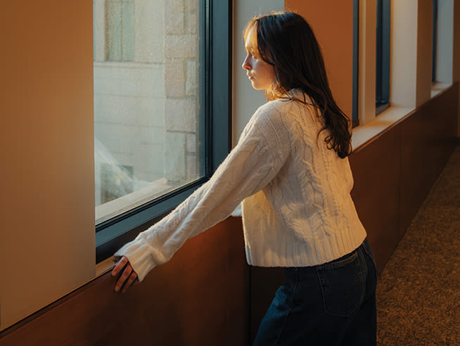 CCU student looks out a window at sunlight