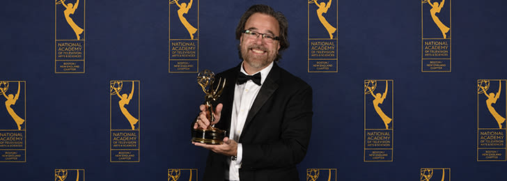 ccu faculty member charlie denler smiling and holding his fifth emmy trophy