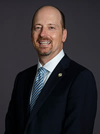 derek hamilton wearing a suit smiling for an official portrait