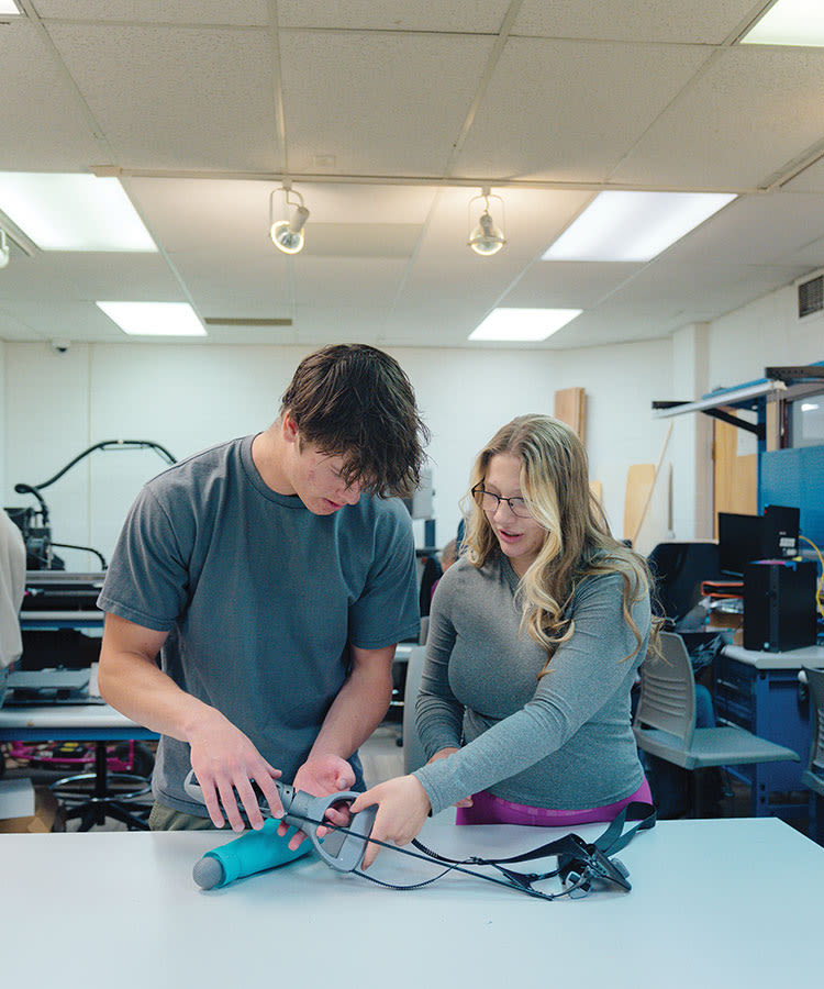 engineering staff and students with bionic arm in classroom