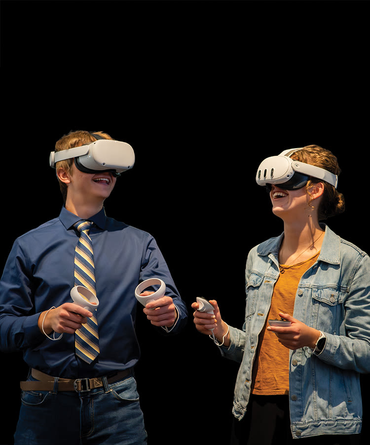 Two students smile and use a VR headset