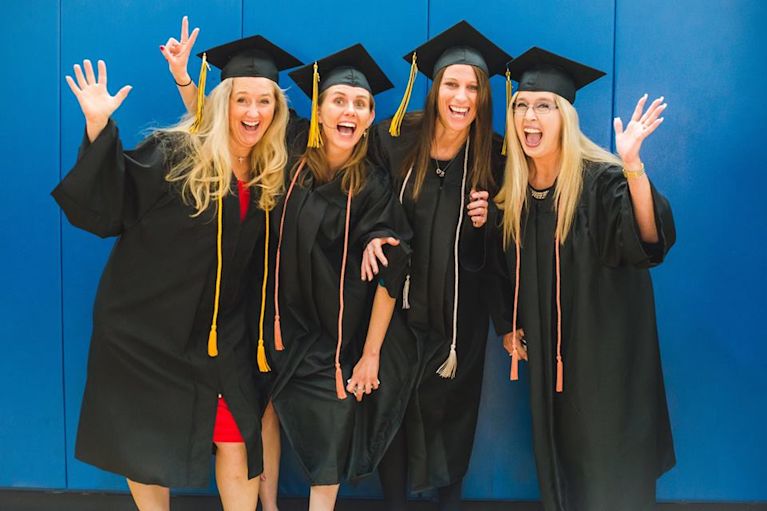 Adult students are posing for a photo at their CCU graduation ceremony.