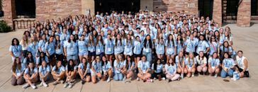 Large group of prospective students posing and smiling on CCU's campus in front of a brick building wearing matching shirts