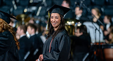 Smiling female graduate walks during ceremony