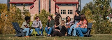 A group of undergraduate students sitting together outside on CCU's campus talking