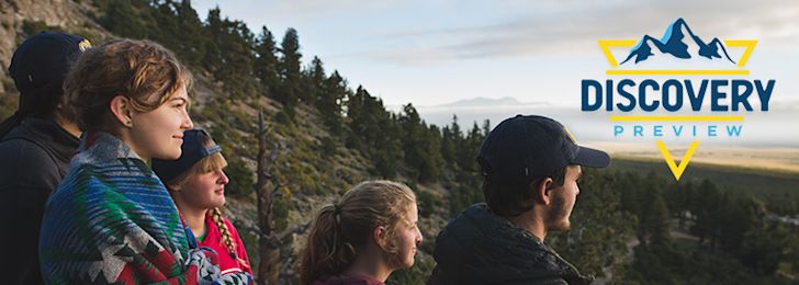 Students on a mountainside, taking part in Discovery Preview event, and looking at the sunset.