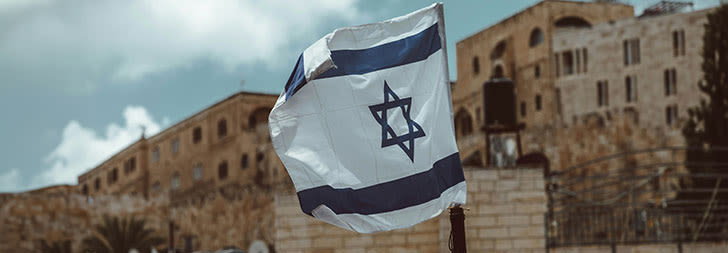 israel flag against a blurred village backdrop