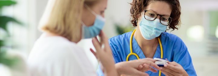 nurse with mask on talking with patient