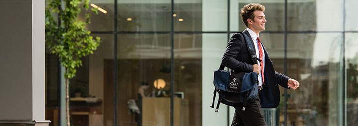 A business man walking with a CCU branded laptop carrier.