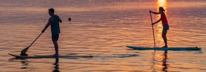 A woman is paddle boarding in the mountains to relieve stress.