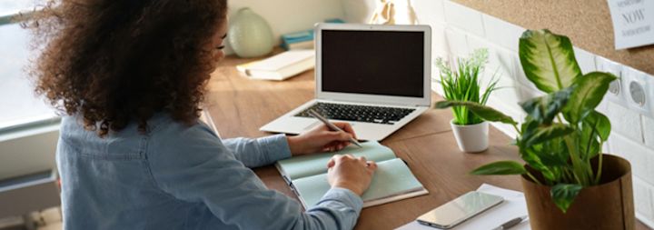 Women at desk on computer with pen and notebook