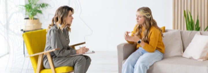 Women and young girl sitting down on chairs talking