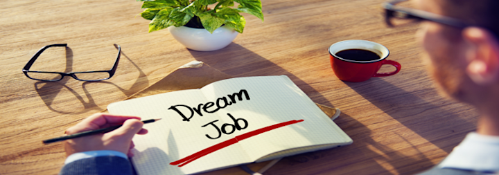 Book open that says dream job and man holding pen