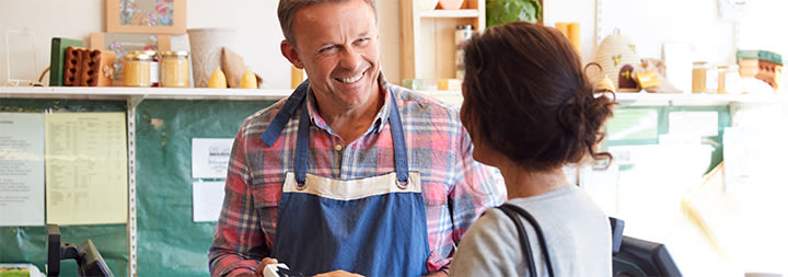 Man smiling at woman tapping her credit card to pay