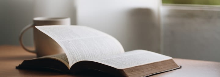 bible open on a table next to a cup of coffee