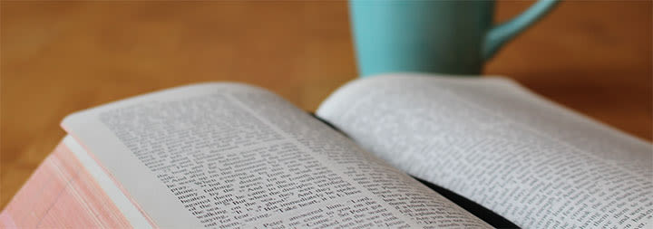 open bible and a blue mug