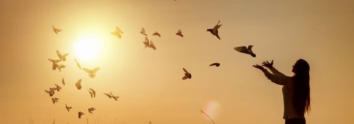 woman standing with birds flying