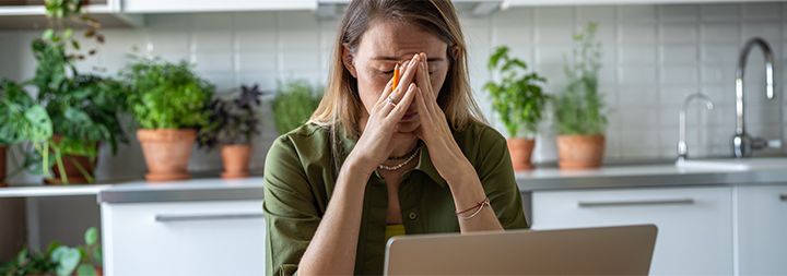 Woman in front of laptop looking very tired