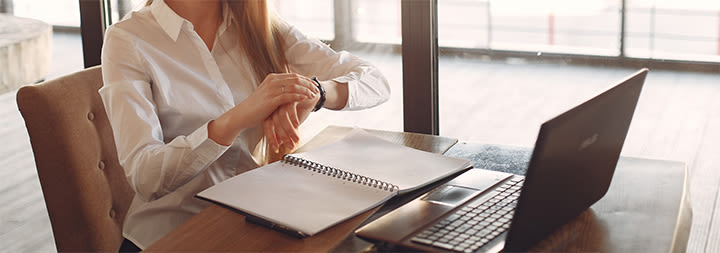 woman working on her laptop checking her watch