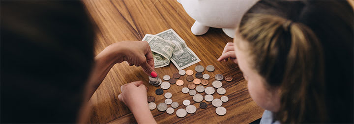 kids counting money at a wooden table