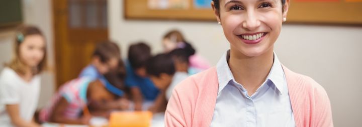 A teacher is standing in a classroom with students.