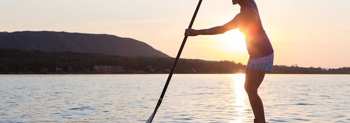 A woman is paddle boarding in the mountains to relieve stress.