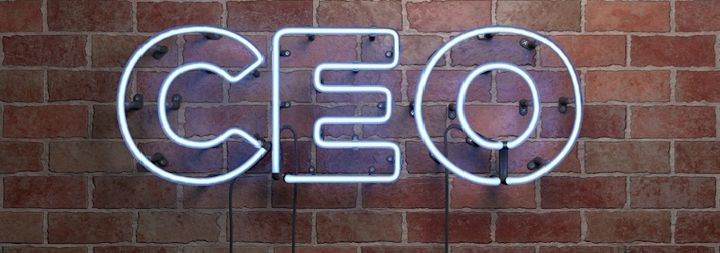 CEO is written on a lit-up sign on a brick wall.
