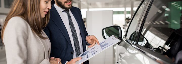 A car salesman is trying to sell a car to a female customer.