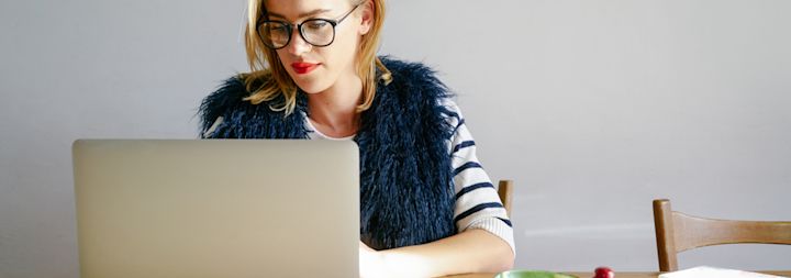 A stylish woman is working on her computer at a desk.