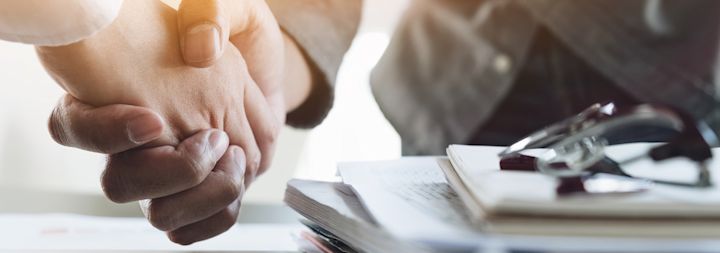 Two men are shaking hands in an office.