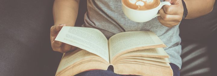 a woman drinking coffee and reading a book