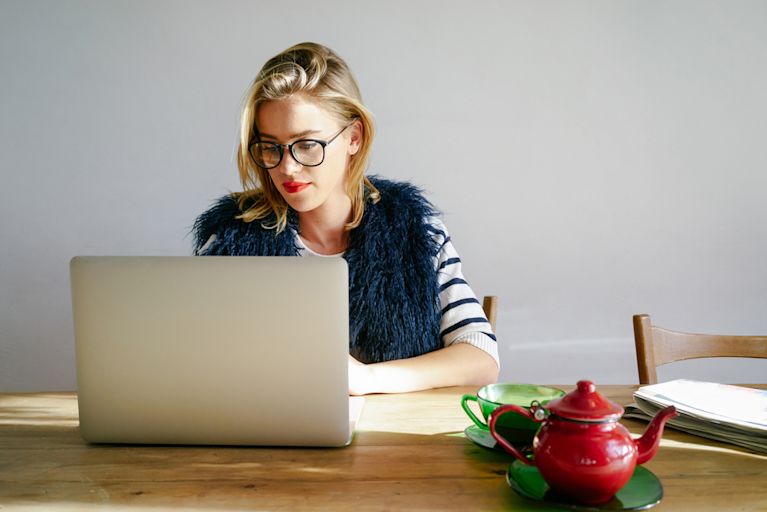 A stylish woman is working on her computer at a desk.