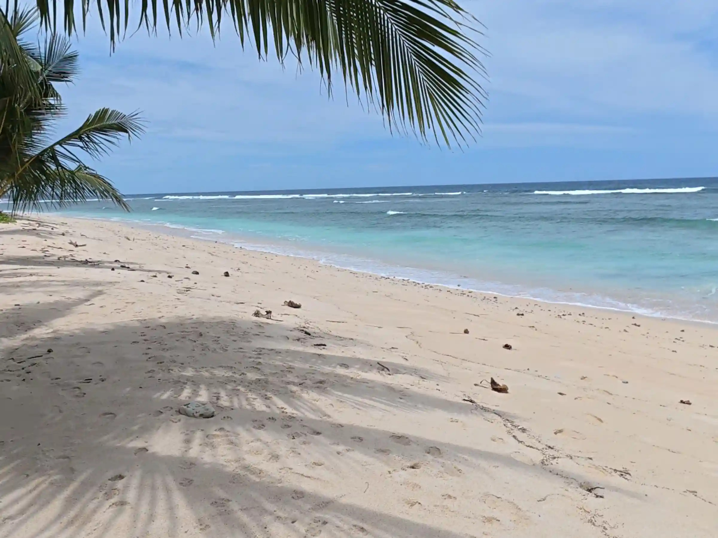 Wide sandy shoreline at Lanca Beach in Mati Davao Oriental with turquoise Pacific waves and a forested headland in the distance