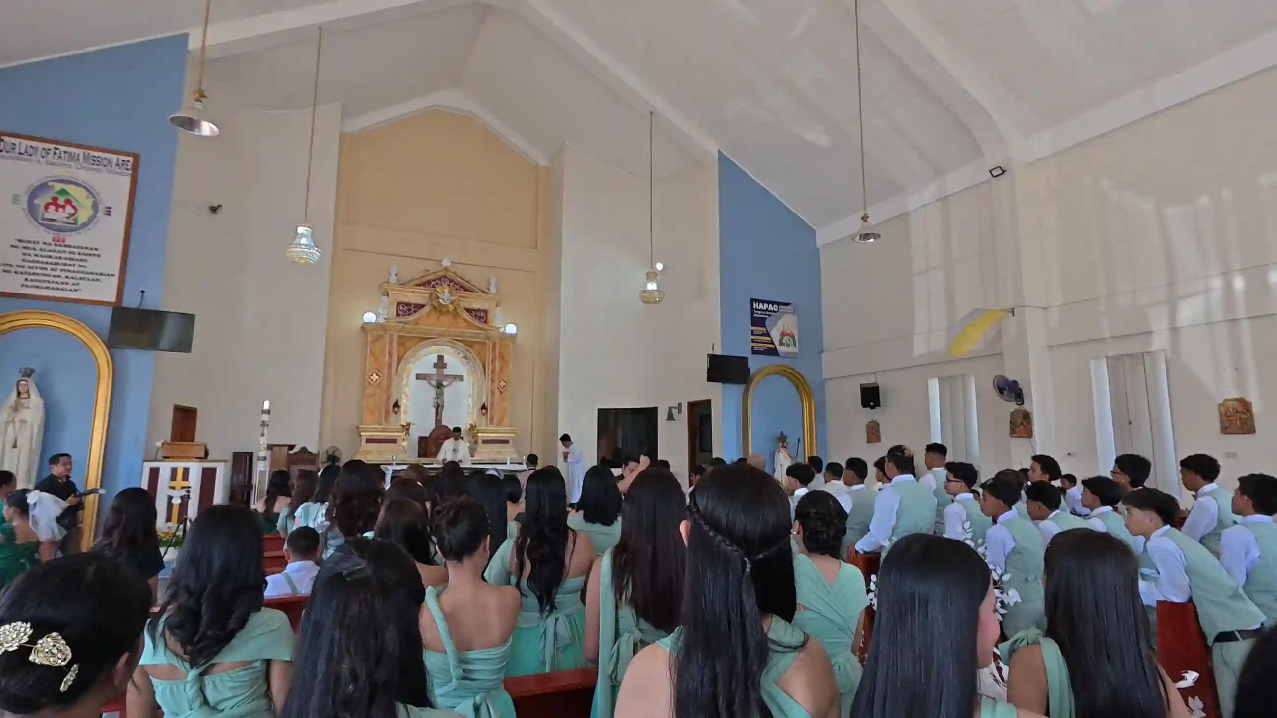 Interior of Our Lady of Fatima Mission Area during the wedding ceremony with bridesmaids in mint green gowns seated in pews facing the altar in Socorro Oriental Mindoro
