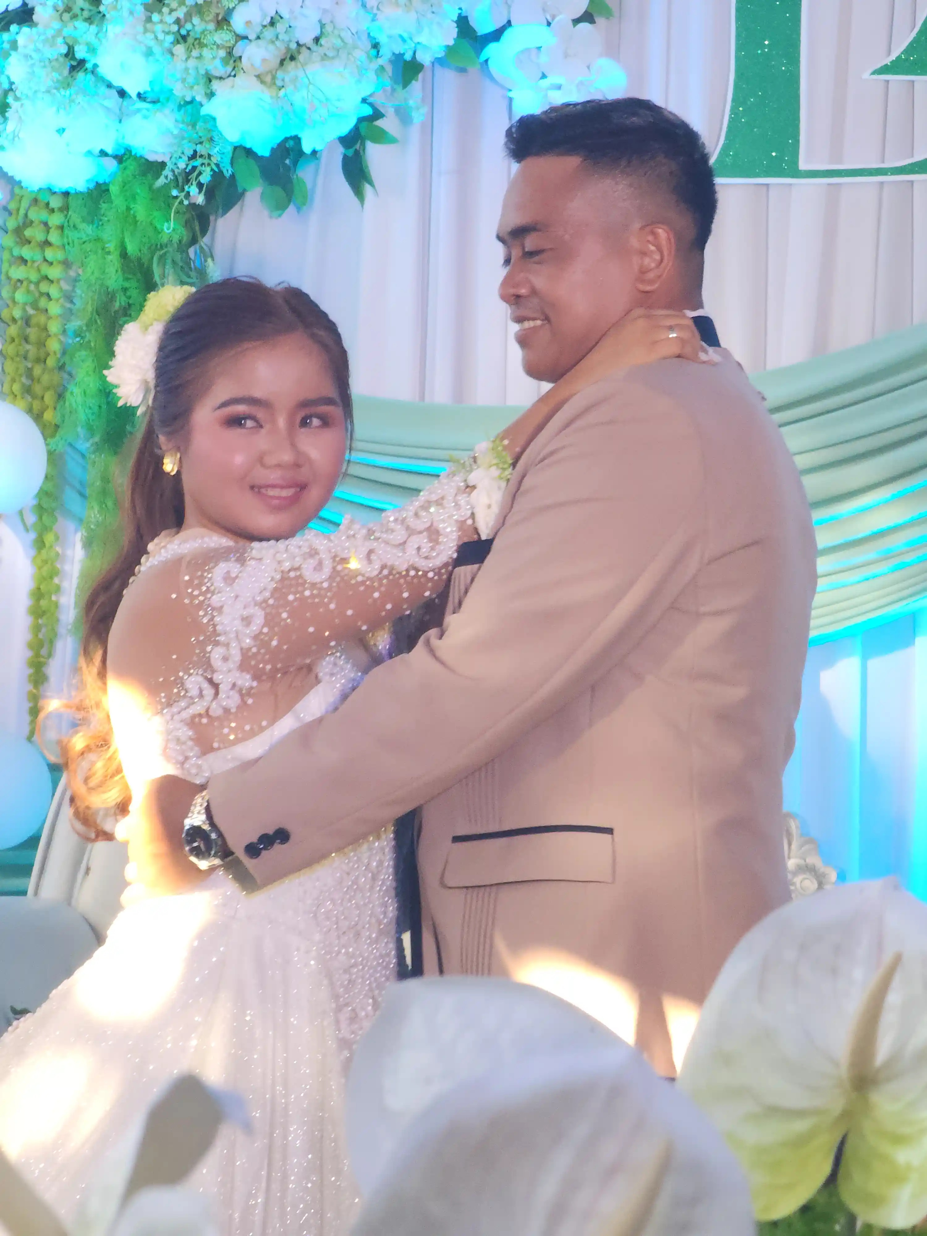 John Aries Almendras and Lyka Isabel Bastida sharing their first dance as a married couple in front of a mint green and white floral backdrop at the reception in Socorro Oriental Mindoro