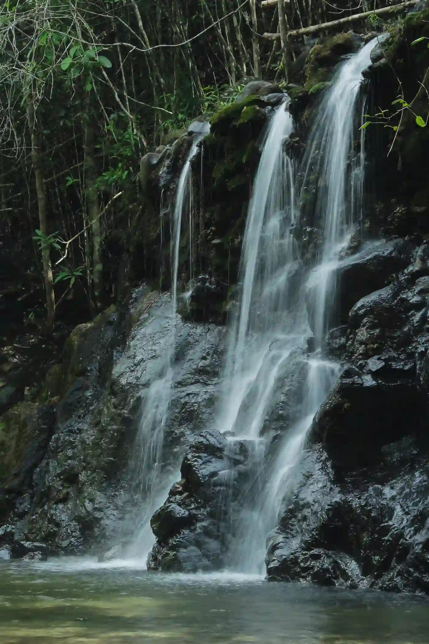 Multi-tiered waterfall at Magkayad Falls in Maputi San Isidro Davao Oriental with white water cascading over dark moss-covered rocks into a shallow natural pool surrounded by dense forest