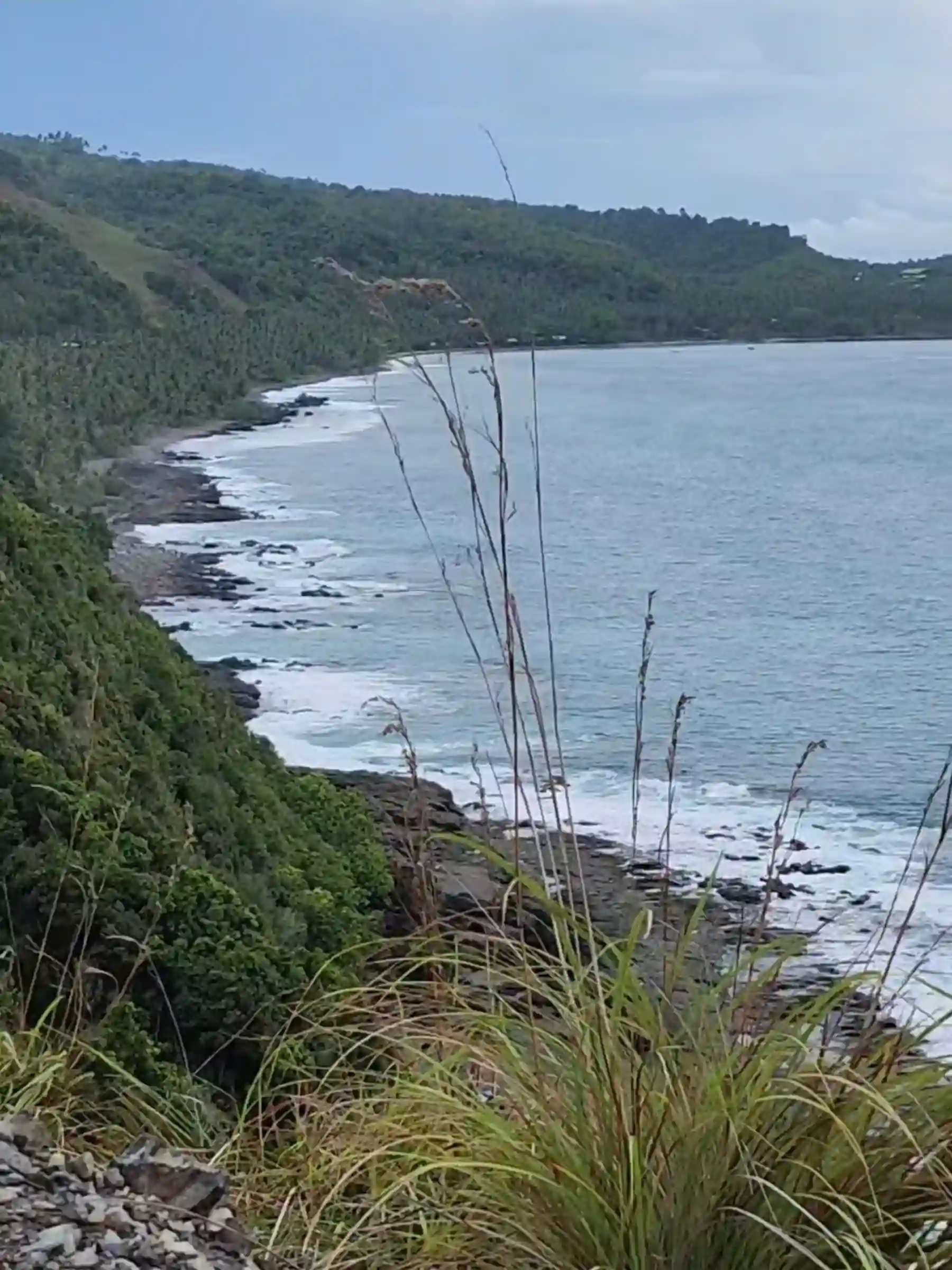Rocky shoreline with white surf and turquoise Pacific water seen from above at the Lanca Cabuaya Road cliffside viewpoint in Mati Davao Oriental