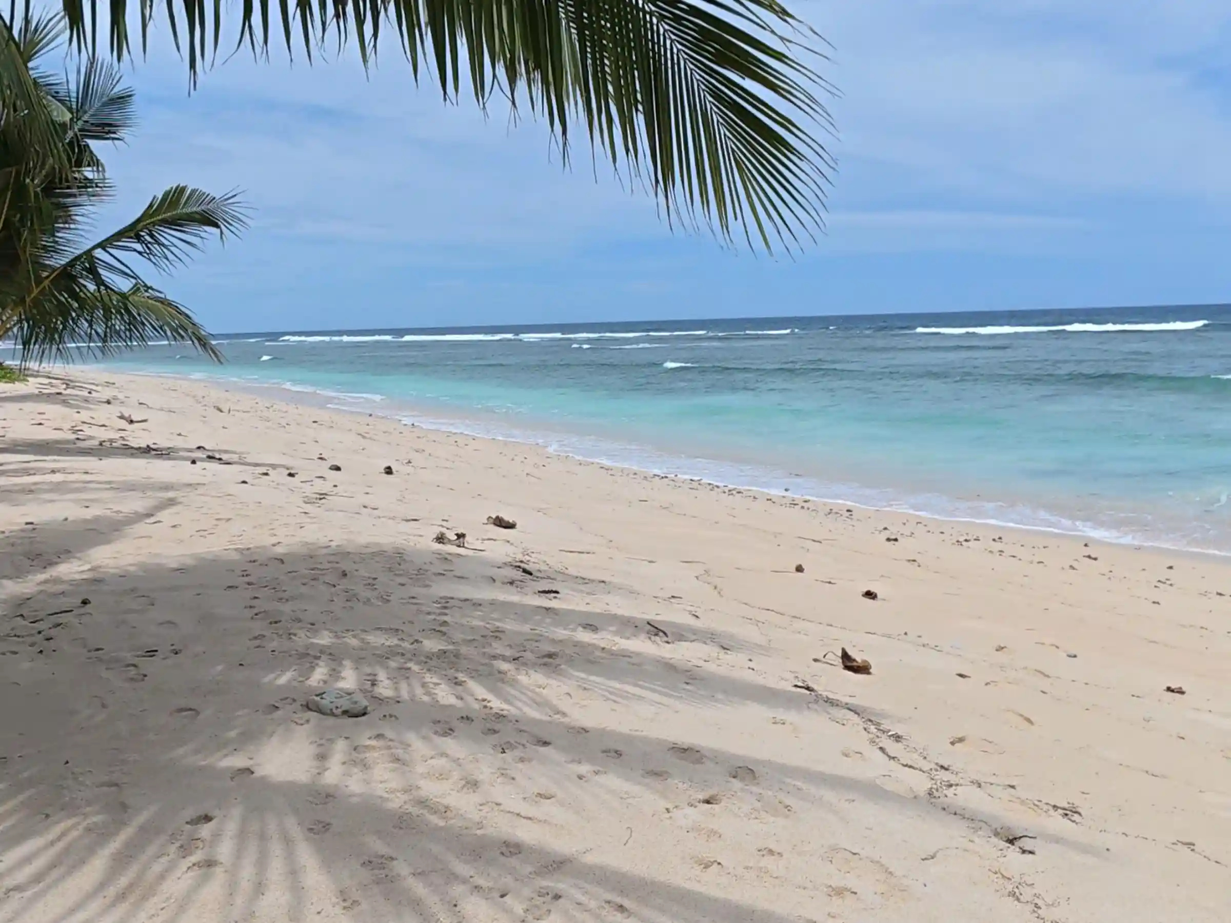 Wide sandy shoreline at Lanca Beach in Mati Davao Oriental with turquoise Pacific waves and a forested headland in the distance