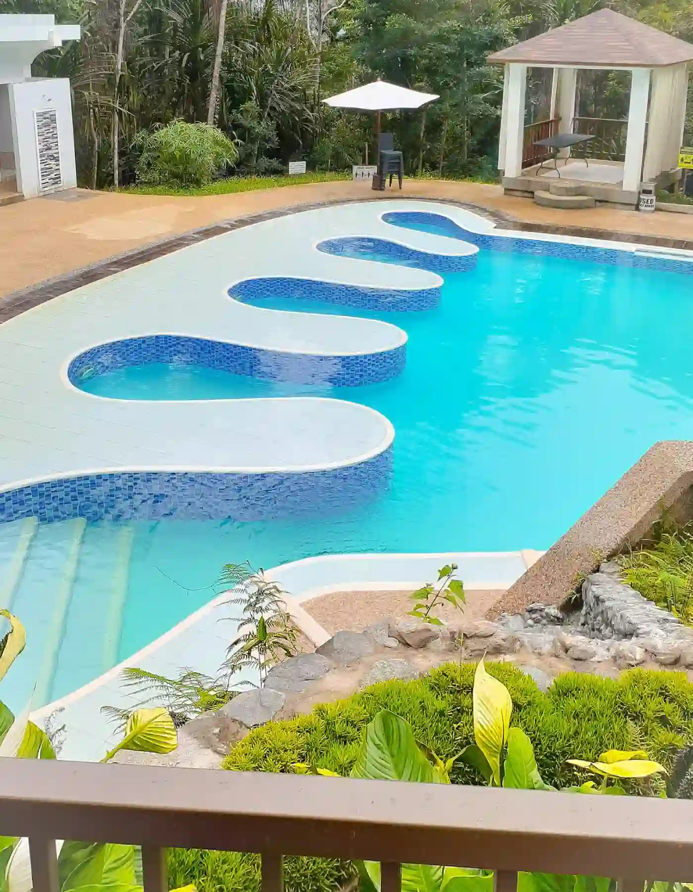 Overhead view showing the wavy freeform shape of the pool at Mt. Hamiguitan Escape Resort with its looped extensions and cobblestone waterfall feature and gazebo in San Isidro Davao Oriental