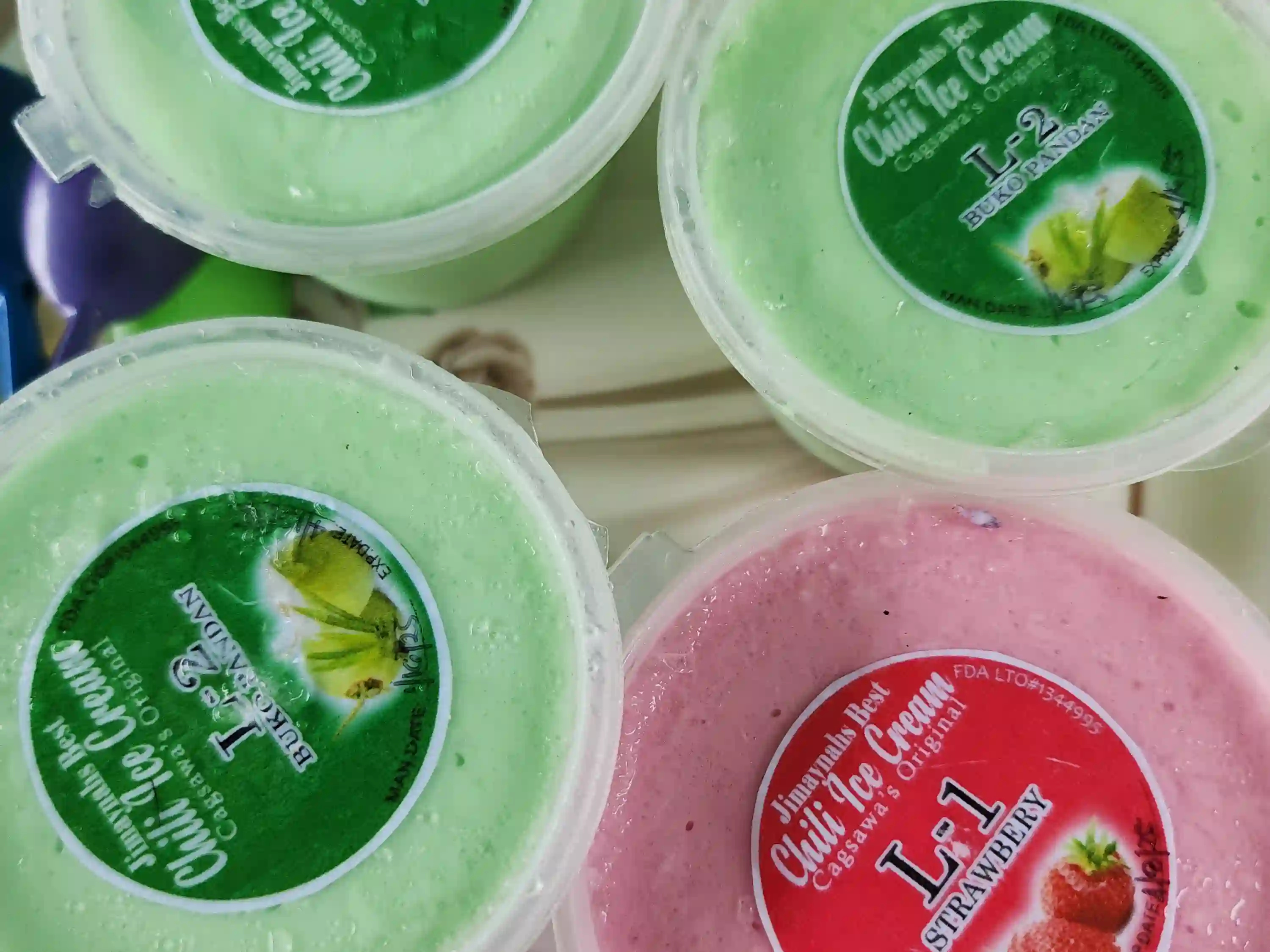 Four cups of Jimaynah chili ice cream in strawberry Level 1 and buko pandan Level 2 varieties on a round plate at a vendor near Cagsawa Ruins in Daraga Albay