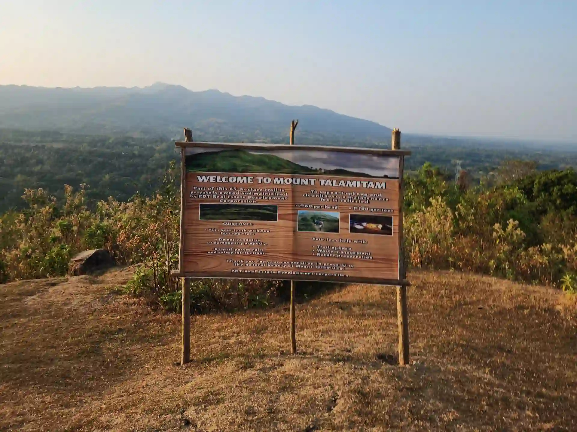 Welcome to Mount Talamitam signboard on open rocky ground with the hazy mountain range visible in the background in Nasugbo Batangas