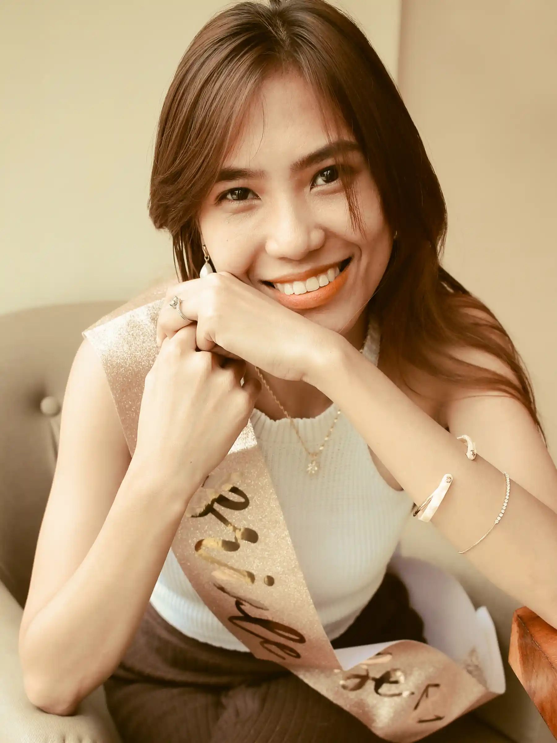 Judy Ann Celorico in a white top seated on a beige armchair in her rose gold bride to be sash at Southwoods Alabang