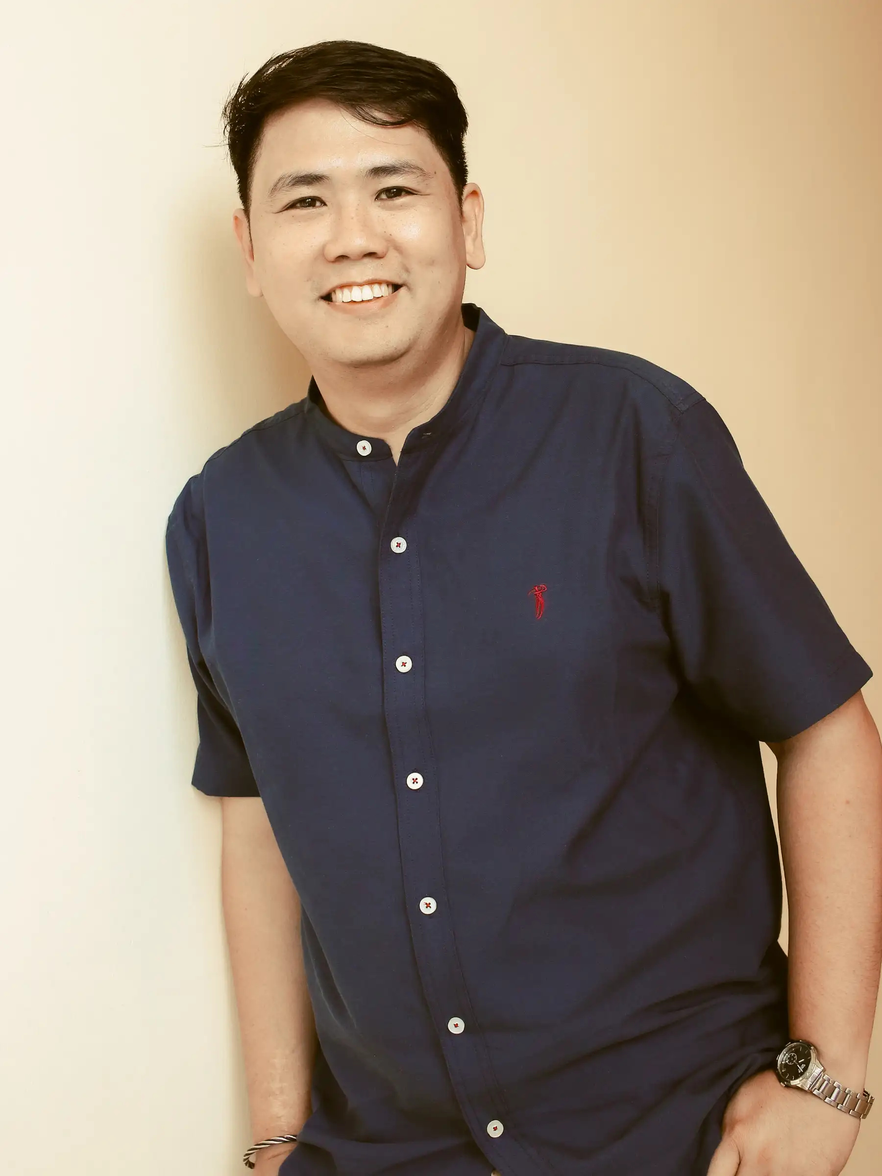 Ryan Lester Celorico in a navy blue short sleeve shirt smiling against a cream wall at Southwoods Alabang