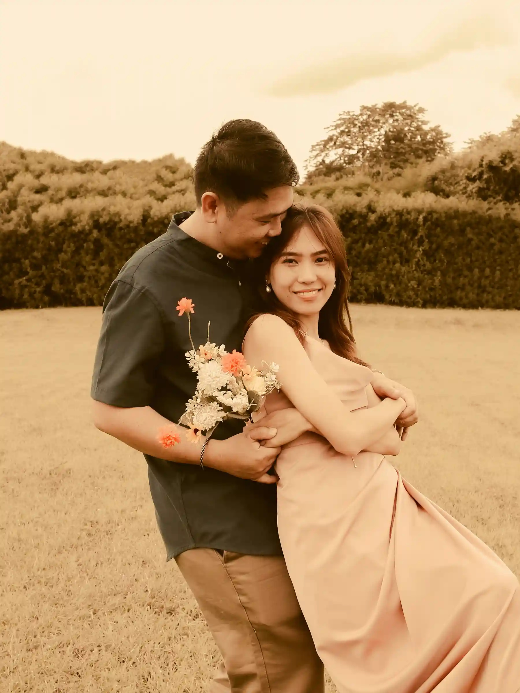 Ryan Lester Celorico embracing Judy Ann from behind holding a bouquet of flowers in an open field at Southwoods Alabang