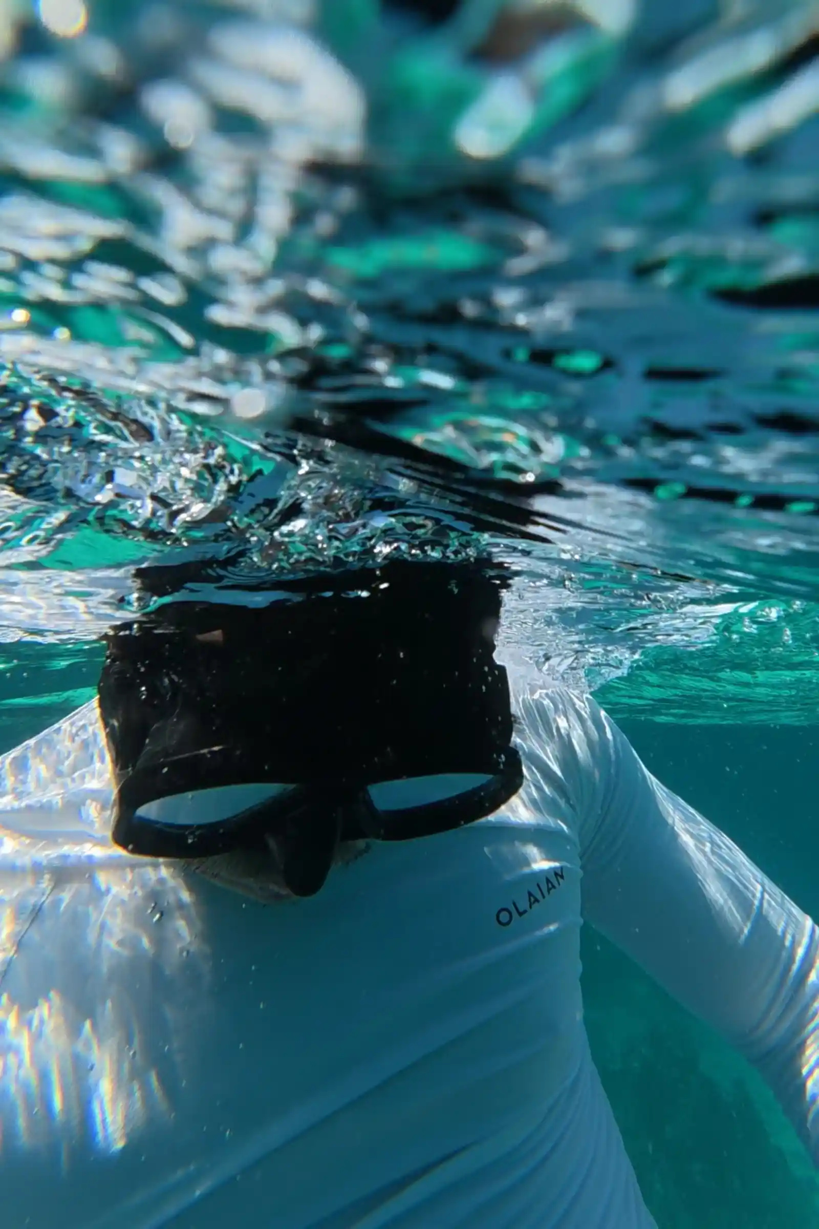 Snorkeler Nelmar Serondo Atanoza at the water surface wearing a black mask with the turquoise water of Balicasag Island Bohol refracted around them from below
