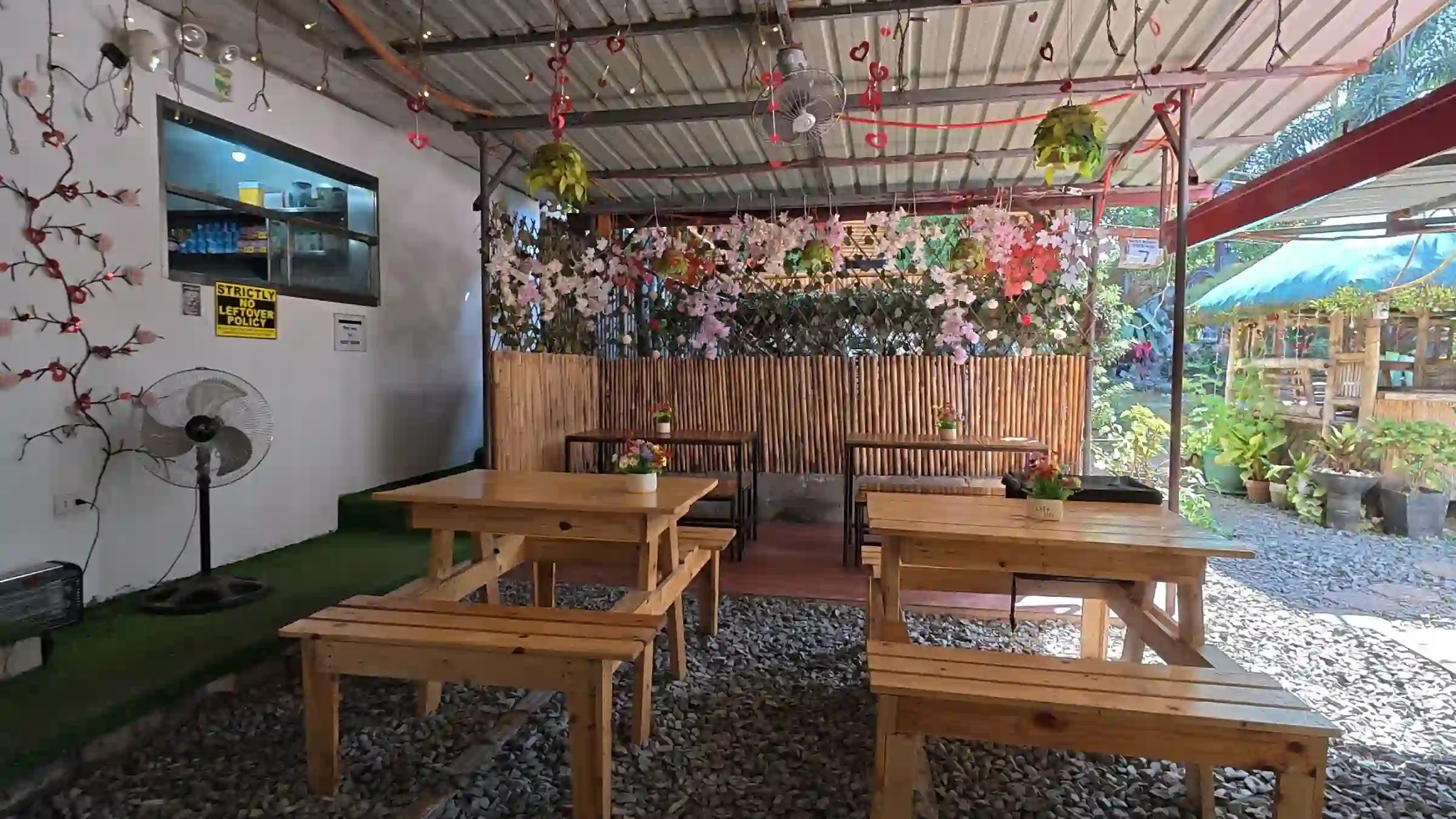 One of the dining areas at Crosswings featuring wooden tables, chairs, bamboo walls, and decorative hanging plants in Alfonso Cavite