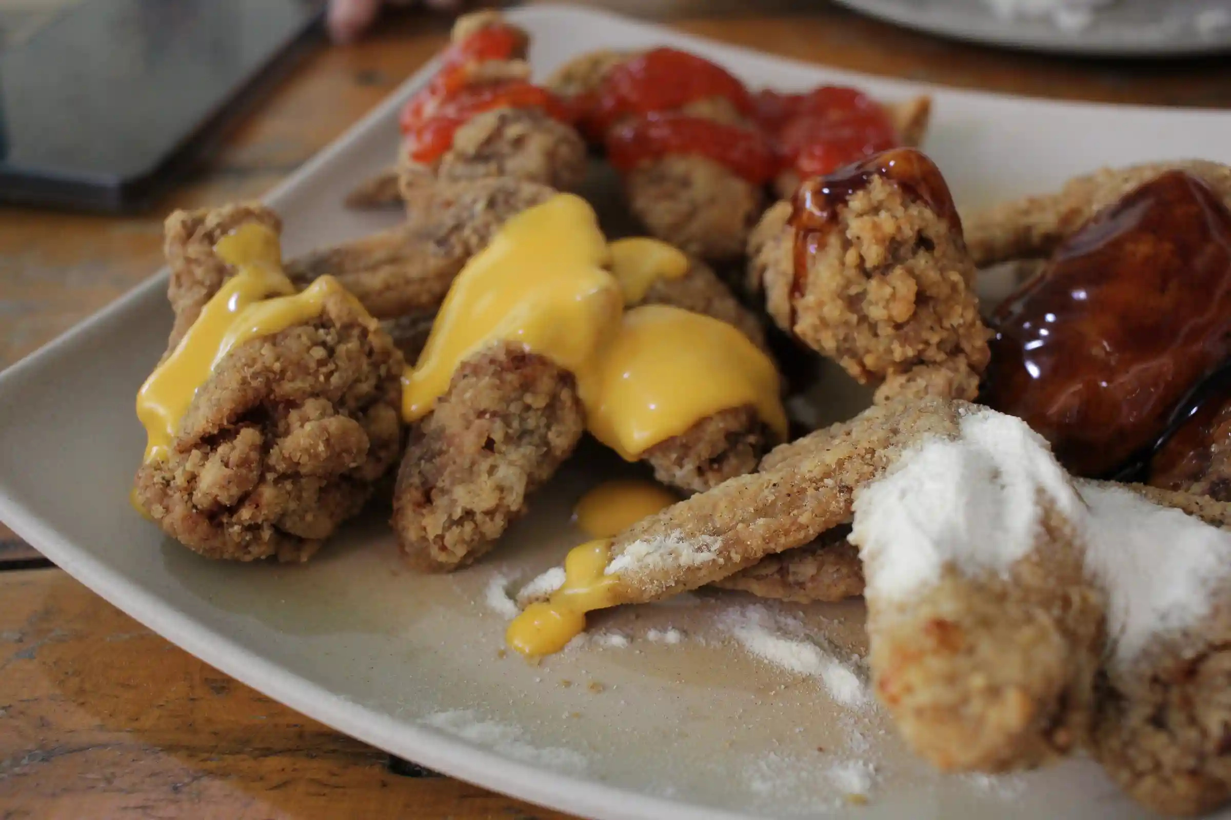 Overhead view of a plate of chicken wings with four flavors including sweet chili cheese BBQ and salted egg at Crosswings Alfonso Cavite
