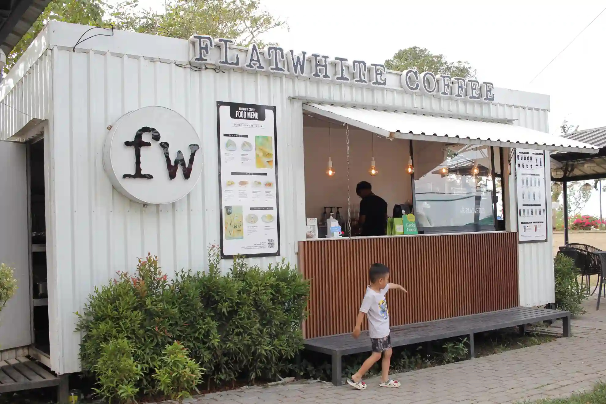 White container kiosk exterior of Flatwhite Coffee with fw logo and food menu board along Tagaytay Nasugbu Highway in Cavite